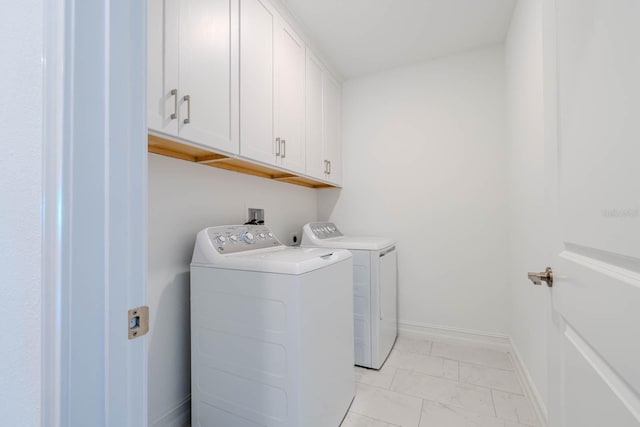 laundry room with marble finish floor, washing machine and dryer, cabinet space, and baseboards