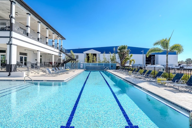 pool with a ceiling fan, a patio, stairway, and fence