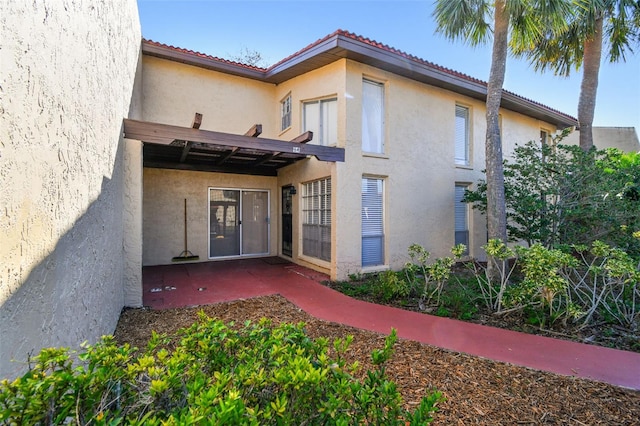 view of exterior entry featuring a patio area and stucco siding