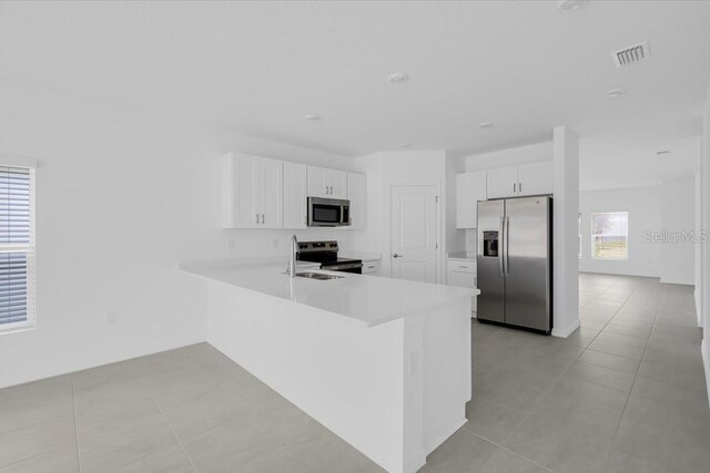 1931 Rosewood Cir, Lakeland, FL 33810 - kitchen featuring stainless steel appliances, light countertops, a peninsula, white cabinetry, and light tile patterned floors