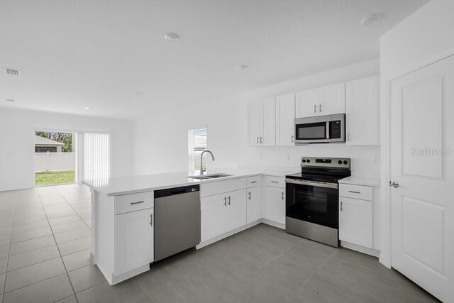 1931 Rosewood Cir, Lakeland, FL 33810 - kitchen with appliances with stainless steel finishes, plenty of natural light, a peninsula, white cabinetry, and recessed lighting