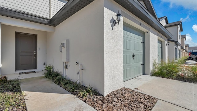 doorway to property featuring a garage and stucco siding