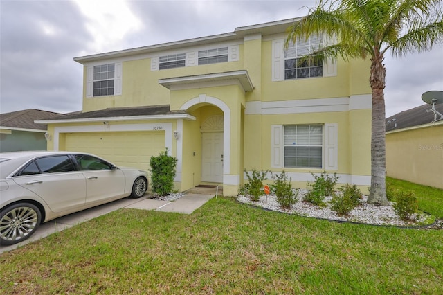 traditional-style home featuring an attached garage, driveway, a front lawn, and stucco siding