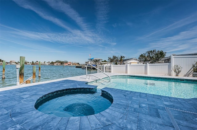 outdoor pool featuring a water view, fence, and an in ground hot tub