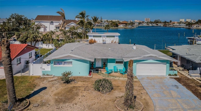 view of front of house with concrete driveway, a water view, an attached garage, fence, and a residential view