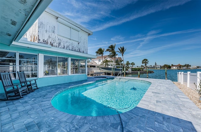 view of pool with a water view, a patio area, and a dock