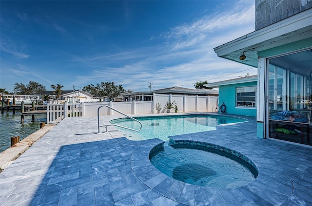 view of swimming pool with a pool with connected hot tub, a water view, fence, and a patio