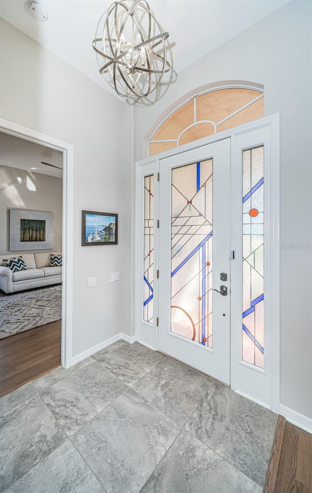 entrance foyer featuring plenty of natural light, a chandelier, baseboards, and wood finished floors