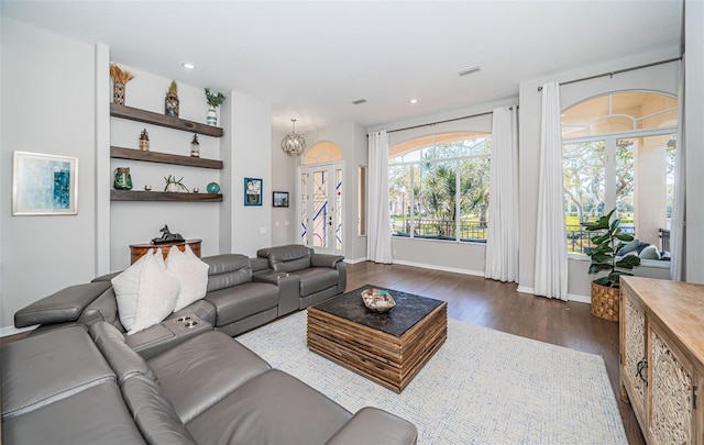 living area featuring recessed lighting, dark wood-style flooring, a notable chandelier, and baseboards