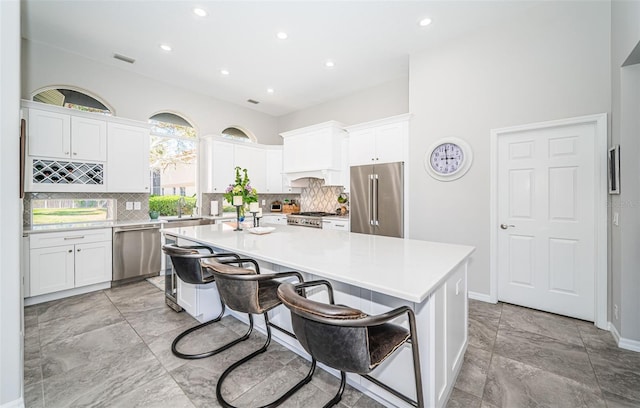 kitchen featuring visible vents, white cabinets, a kitchen island, appliances with stainless steel finishes, and a breakfast bar area