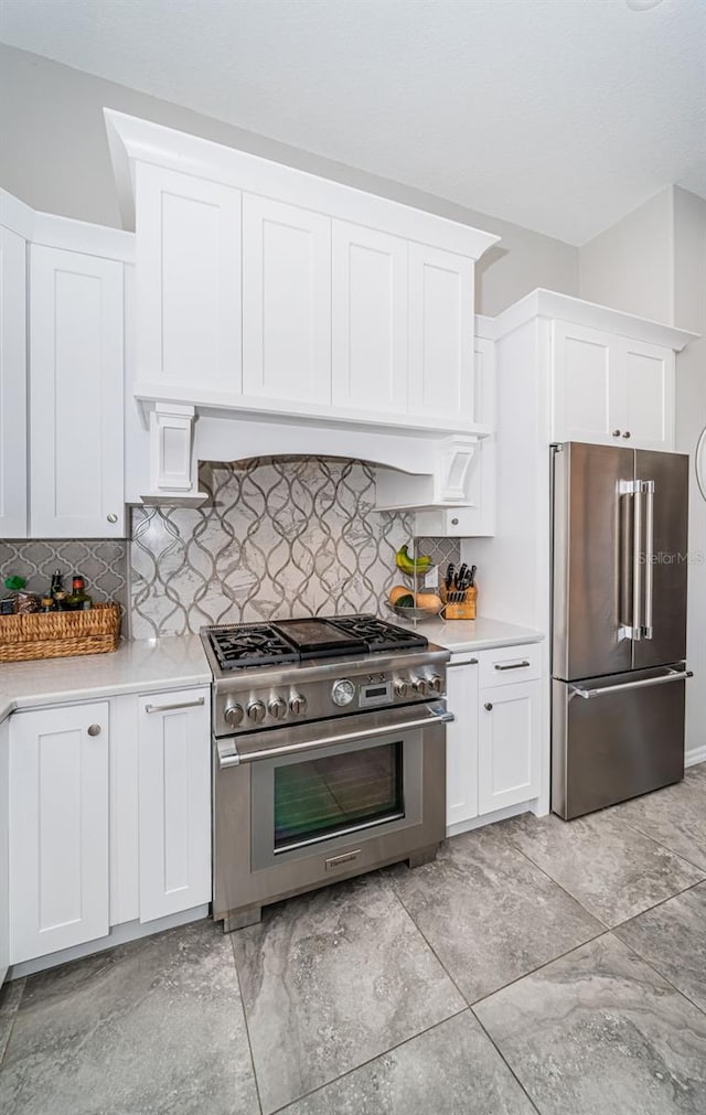 kitchen featuring extractor fan, white cabinets, light countertops, decorative backsplash, and high end appliances