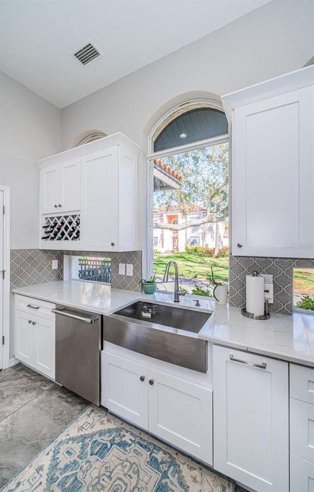 kitchen featuring visible vents, dishwasher, a sink, and white cabinetry