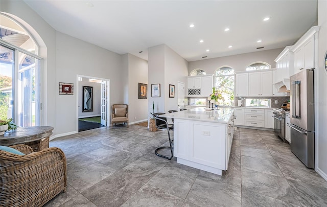 kitchen with tasteful backsplash, a kitchen island, high quality appliances, a kitchen breakfast bar, and white cabinetry