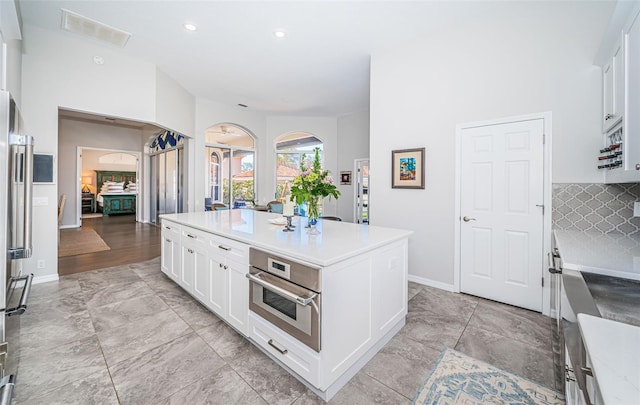 kitchen featuring visible vents, white cabinetry, light countertops, appliances with stainless steel finishes, and a center island