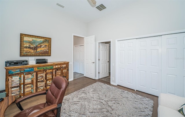 office space with baseboards, visible vents, and wood finished floors