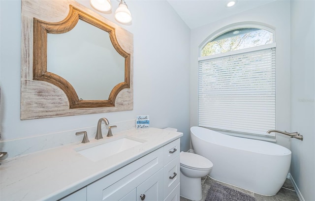 full bathroom featuring a soaking tub, vanity, and toilet