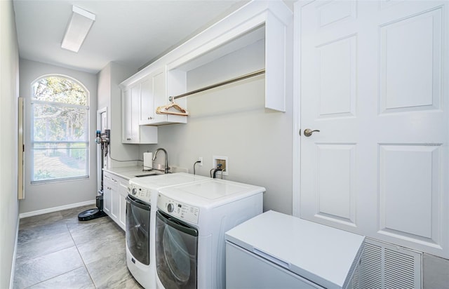 laundry room with cabinet space, baseboards, separate washer and dryer, and a sink