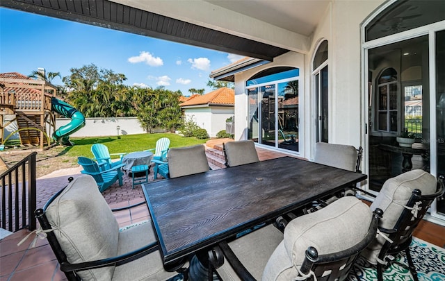 view of patio / terrace featuring outdoor dining area, a playground, and fence