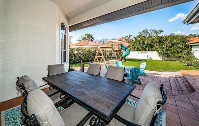 view of patio / terrace featuring fence, a playground, and outdoor dining space