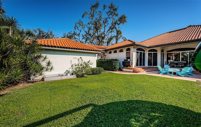 back of property with a tiled roof, a yard, a patio area, and stucco siding