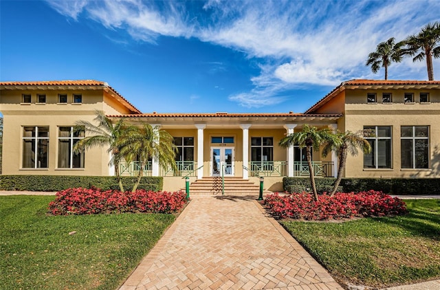 view of front of property featuring a front yard, covered porch, french doors, and stucco siding