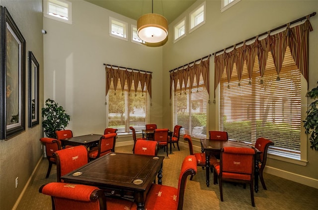 dining space featuring a healthy amount of sunlight, a towering ceiling, and baseboards