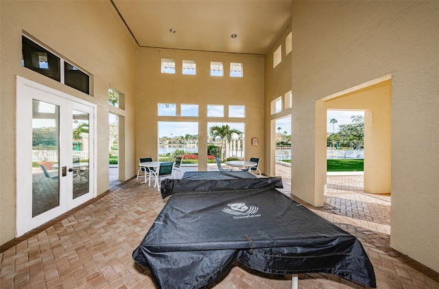 sunroom / solarium with french doors, a water view, and plenty of natural light