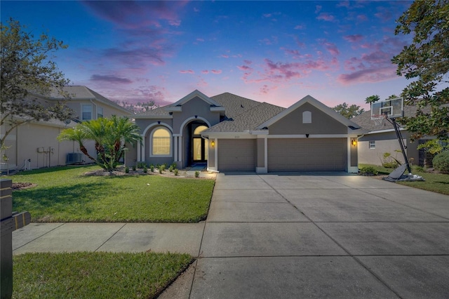 view of front of house with stucco siding, concrete driveway, a garage, central air condition unit, and a lawn