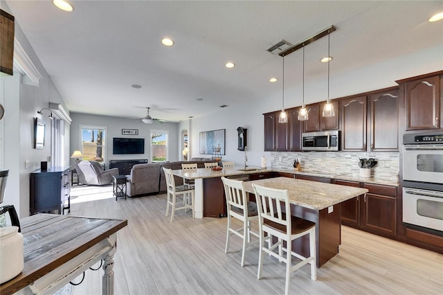 kitchen featuring open floor plan, stainless steel appliances, a kitchen bar, and decorative backsplash