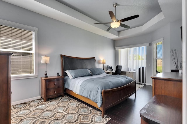 bedroom featuring baseboards, ceiling fan, access to exterior, dark wood-type flooring, and a raised ceiling