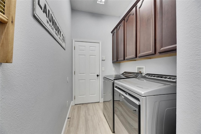 laundry room with light wood-type flooring, washer and dryer, cabinet space, baseboards, and a textured wall