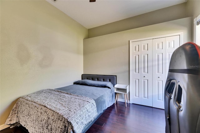 bedroom with a closet, dark wood-type flooring, and baseboards