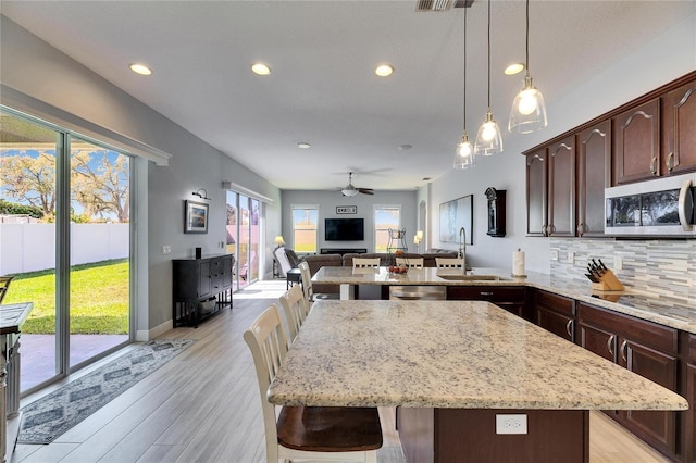 kitchen with light stone counters, decorative backsplash, appliances with stainless steel finishes, and a sink