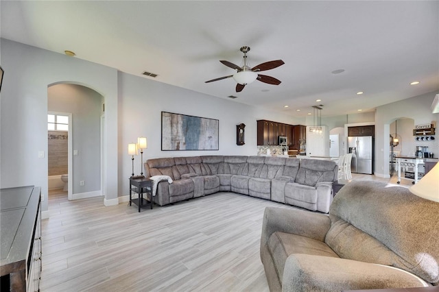 living area with visible vents, recessed lighting, light wood-style floors, and arched walkways