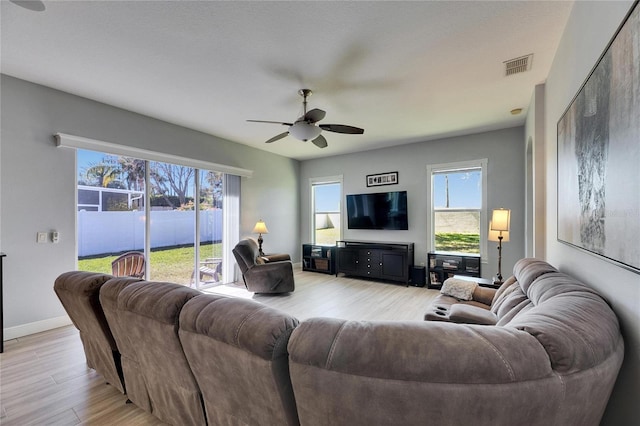 living area with baseboards, visible vents, light wood finished floors, and ceiling fan