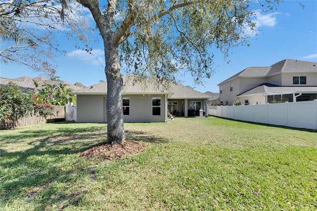 back of property with a lawn, a fenced backyard, and stucco siding