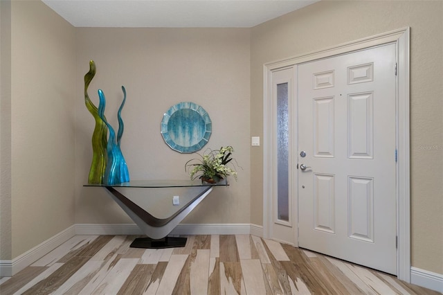 foyer featuring baseboards and wood finished floors