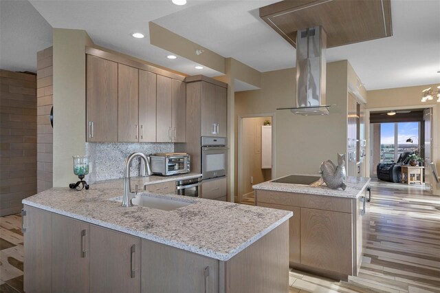 4951 Bacopa Ln S Unit 801, Saint Petersburg, FL 33715 - kitchen with backsplash, light stone counters, a peninsula, island exhaust hood, and a sink