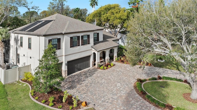 view of front of property featuring an attached garage, fence, roof with shingles, decorative driveway, and stucco siding