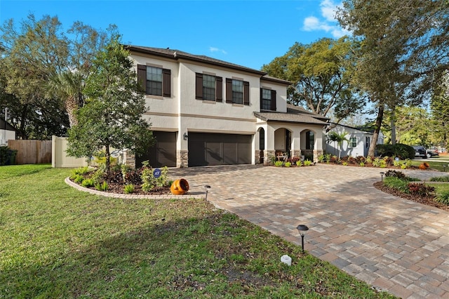 view of front of home with a garage, fence, stone siding, decorative driveway, and stucco siding