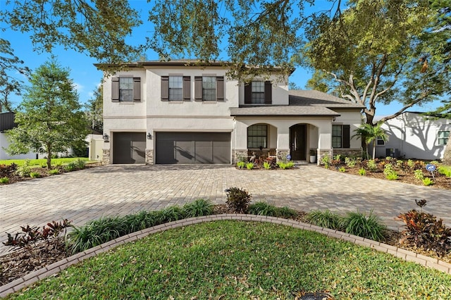 view of front of property with an attached garage, stone siding, decorative driveway, and stucco siding