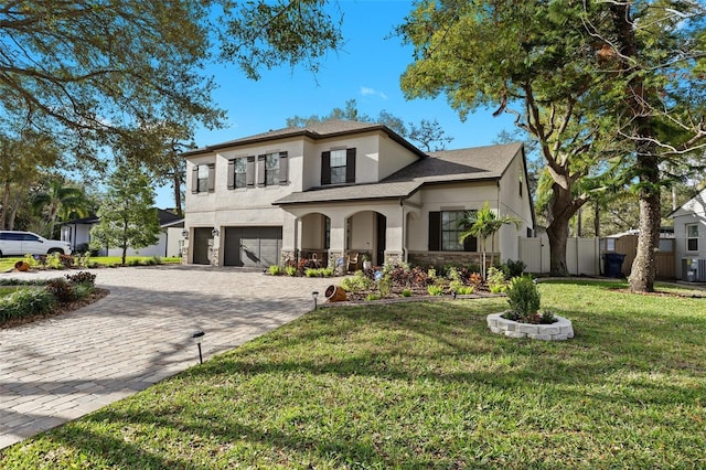 view of front facade with a garage, stone siding, decorative driveway, a front lawn, and stucco siding