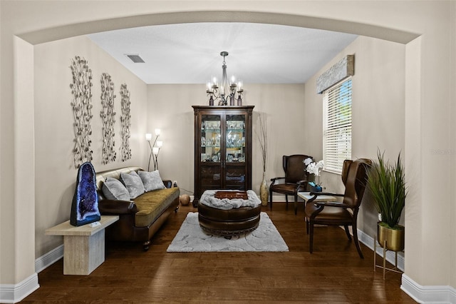 living area featuring a chandelier, arched walkways, visible vents, and wood finished floors