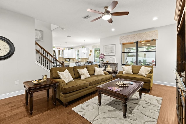 living room with baseboards, visible vents, a ceiling fan, stairway, and wood finished floors