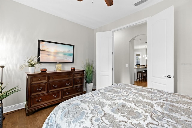 bedroom featuring arched walkways, dark wood-style flooring, visible vents, a ceiling fan, and baseboards