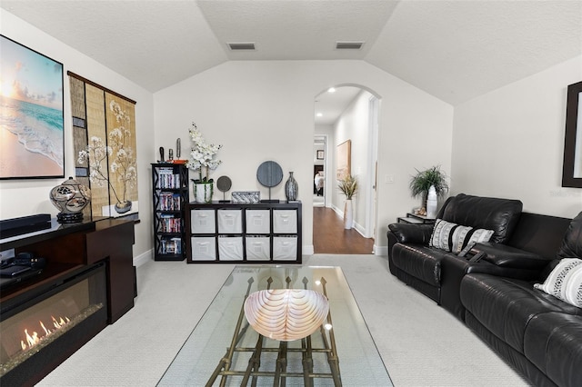 living area with arched walkways, visible vents, and vaulted ceiling