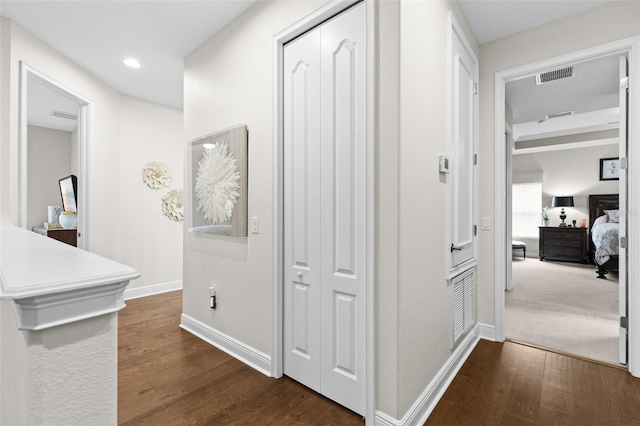 hall with dark wood-type flooring, recessed lighting, visible vents, and baseboards