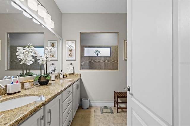 full bathroom featuring double vanity, baseboards, and a sink