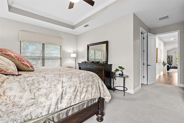 bedroom featuring arched walkways, carpet floors, visible vents, baseboards, and a tray ceiling