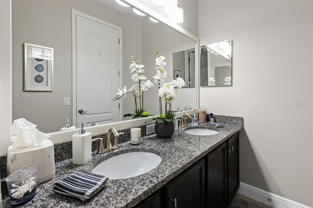 full bath featuring a sink, baseboards, and double vanity